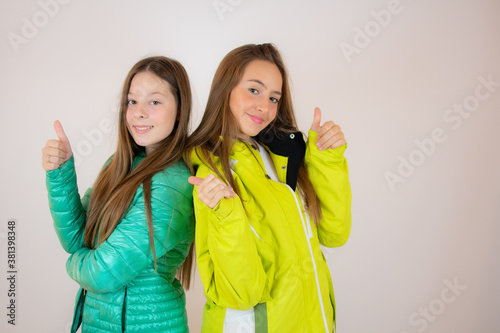 Two smiling friends in winter jackets on white background