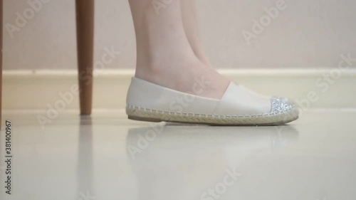 female feet in white shoes shaking on white floor. foot tapping concept.