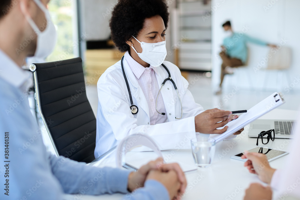 African American doctor going through medical record while having appointment with a couple. African American doctor going through medical record while having appointment with a couple.
