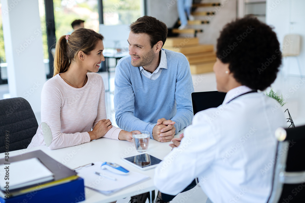 Happy couple talking while having appointment with a doctor at the clinic. Happy couple talking while having appointment with a doctor at the clinic.
