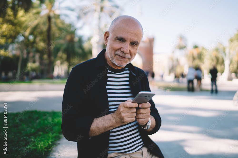 Happy aged man using smartphone in modern park Happy aged man using smartphone in modern park