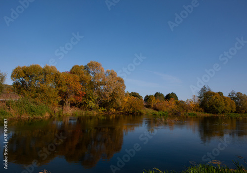 Colorful reflection of the autumn forest and blue sky in the river. Russia