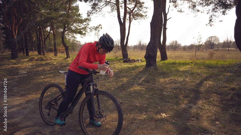The topic health problems with athletes. Caucasian woman cyclist on mountain bike finish workout in forest. Emotion tired, hard fast heart beating and hard to breathe. Cardiac pathology tachycardia
