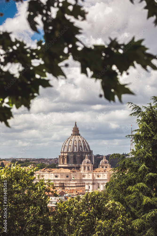 Fototapeta premium Dome of St. Peter in the Vatican city in Rome in Italy in the middle of the trees. Renovation works in the cathedral with scaffolding.