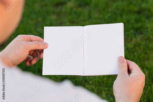 Layout of the cover of the magazine, catalog, book. a man reading a blank magazine, catalog, book sitting on a green lawn