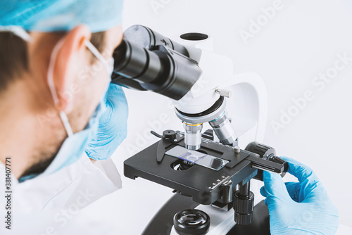 Scientist looks through a microscope in a laboratory. Medical and pharmaceutical concept. Laboratory research, medical and scientific research. Blood, virus, biology tests.