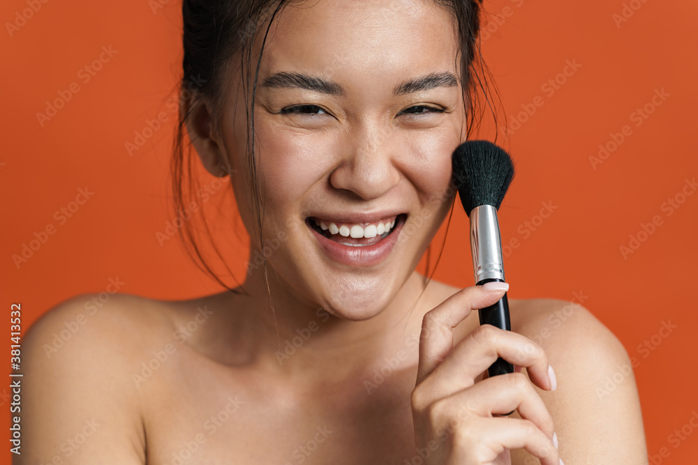 Image of cheerful shirtless asian girl posing with powder brush Image of cheerful shirtless asian girl posing with powder brush