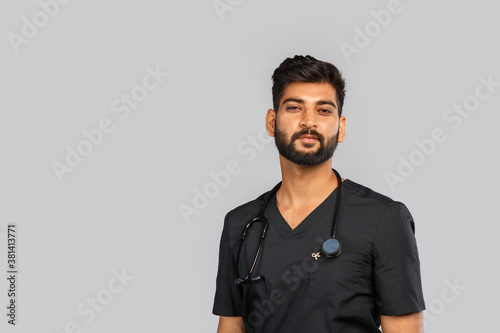 young indian male doctor or surgeon with stethoscope on gray background