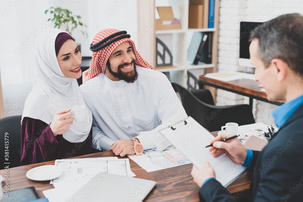 Family sits at a table in front of realtor smiling Family sits at a table in front of realtor smiling
