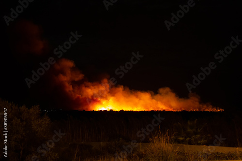 Wildfire at night with large amounts of smoke and large expanse. Ecological disaster concept