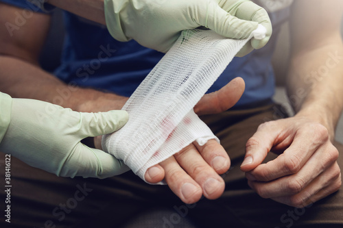 Fotografiet first aid - doctor traumatologist bandaging patient injured hand