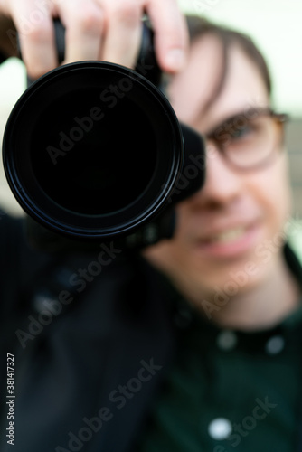 Young white man holding a camera. Reportage photography on the street. Selective focus.
