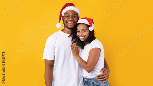 African American Couple In Red Santa Hats Standing, Studio Shot © Prostock-studio
