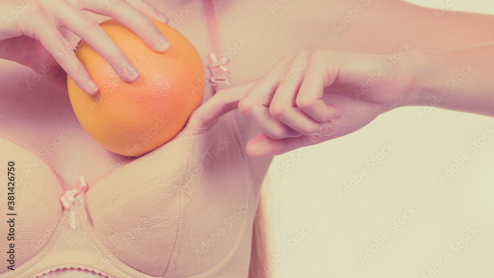 Woman small boobs puts big fruit in her bra Stock Photo