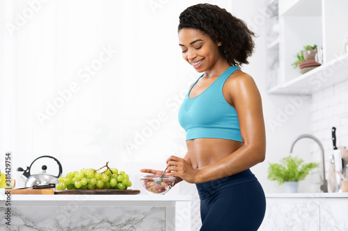 Black woman eating granola with yogurt in bowl