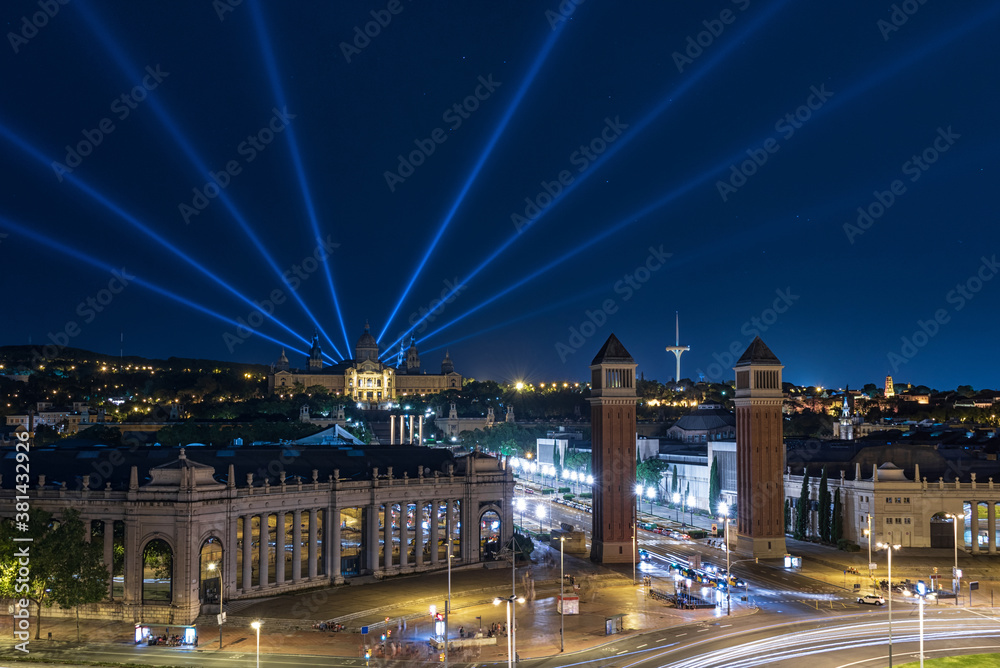 Barcelona, panorama from the Plaza de Espana (Spain Square) to Montjuic and the National Art Museum of Catalonia with beams of searchlights cutting through the dark sky.