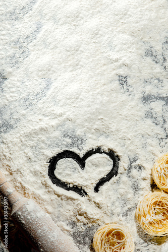 Heart of flour and rolling pin on black background. Top view  copy space