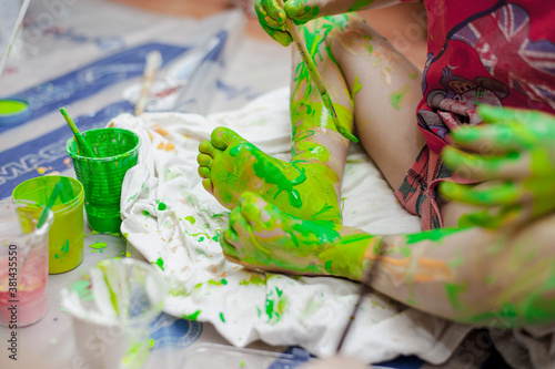 painted children's feet in green. Baby draws with a brush on his own