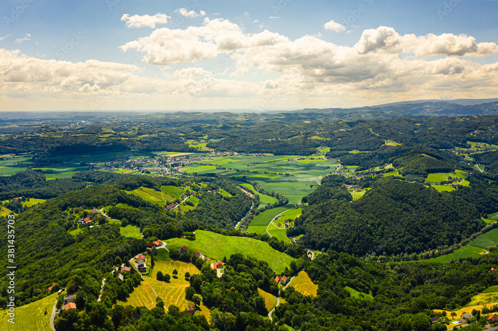 Aerial view of green hills and vineyards with mountains in background.