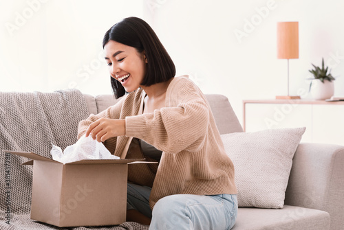 Happy asian lady unpacking parcel after online shopping photo