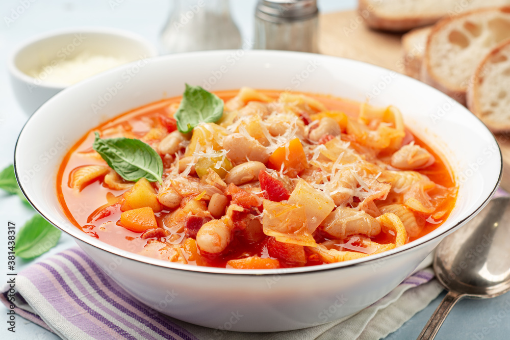 Italian minestrone soup with parmesan cheese and basil on blue concrete background Italian minestrone soup with parmesan cheese and basil on blue concrete background