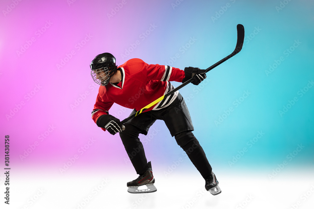 On fire. Male hockey player with the stick on ice court and neon gradient background. Sportsman wearing equipment, helmet practicing. Concept of sport, healthy lifestyle, motion, wellness, action.