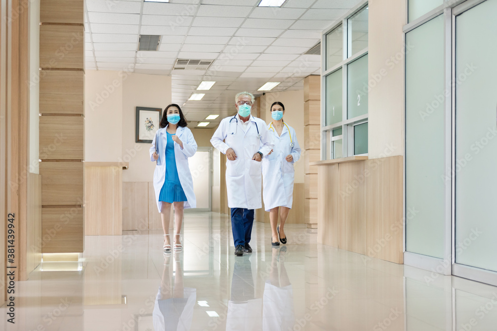 Three doctors with mask running in a lobby. Doctors rushing for emergency in hospital. Moving focus, blurry too soft.