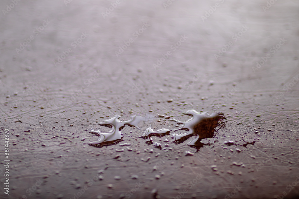 Small and large drops of rain on a wooden surface. Close-up with blurred background.