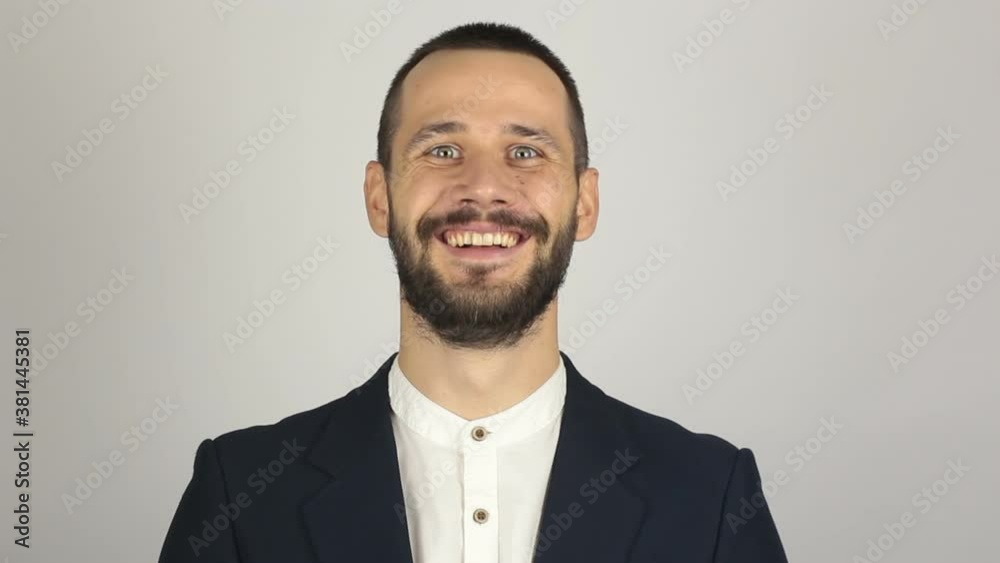 A young handsome businessman in a blue suit is looking at the camera and laughing. A young handsome businessman in a blue suit is looking at the camera and laughing.