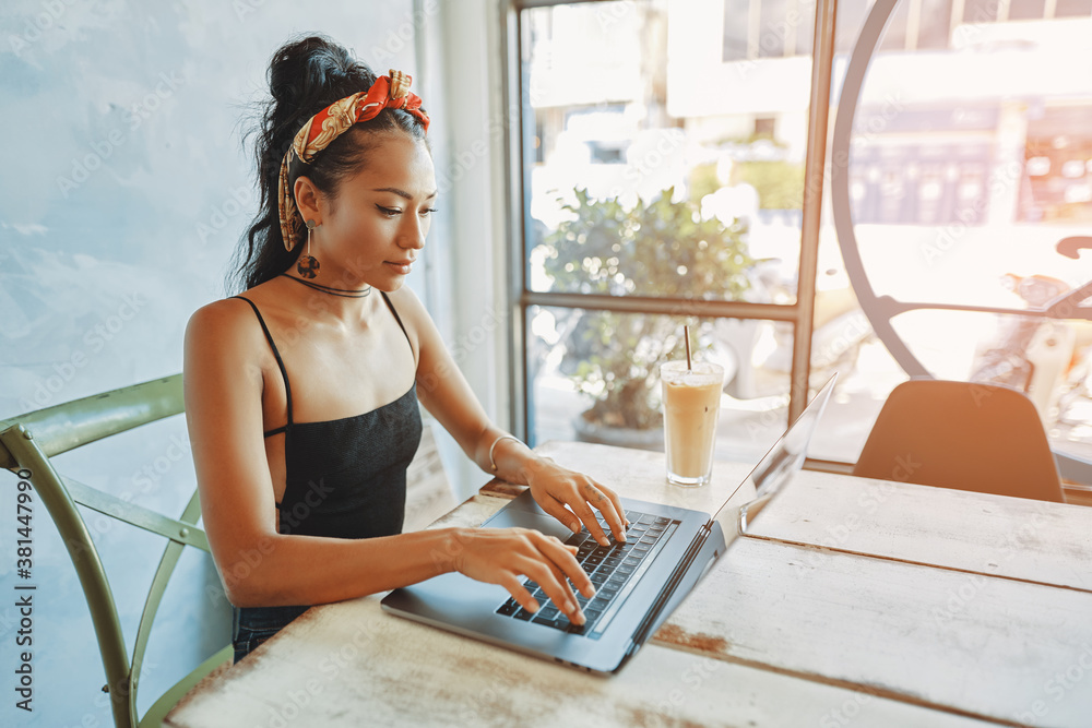 a young asian woman using her laptop in cafe