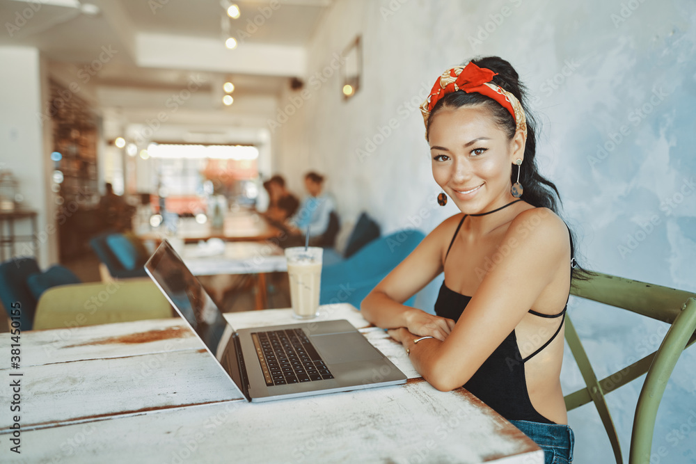 a young asian woman using her laptop in cafe