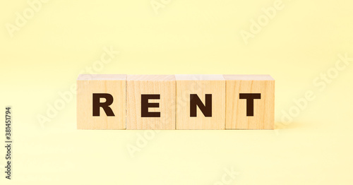 word rent with letters on wooden blocks on bright yellow