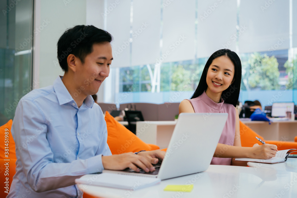 Asian businessman and woman smiling and working together, writing in notebook, collaboration, cooperation, teamwork Asian businessman and woman smiling and working together, writing in notebook, collaboration, cooperation, teamwork