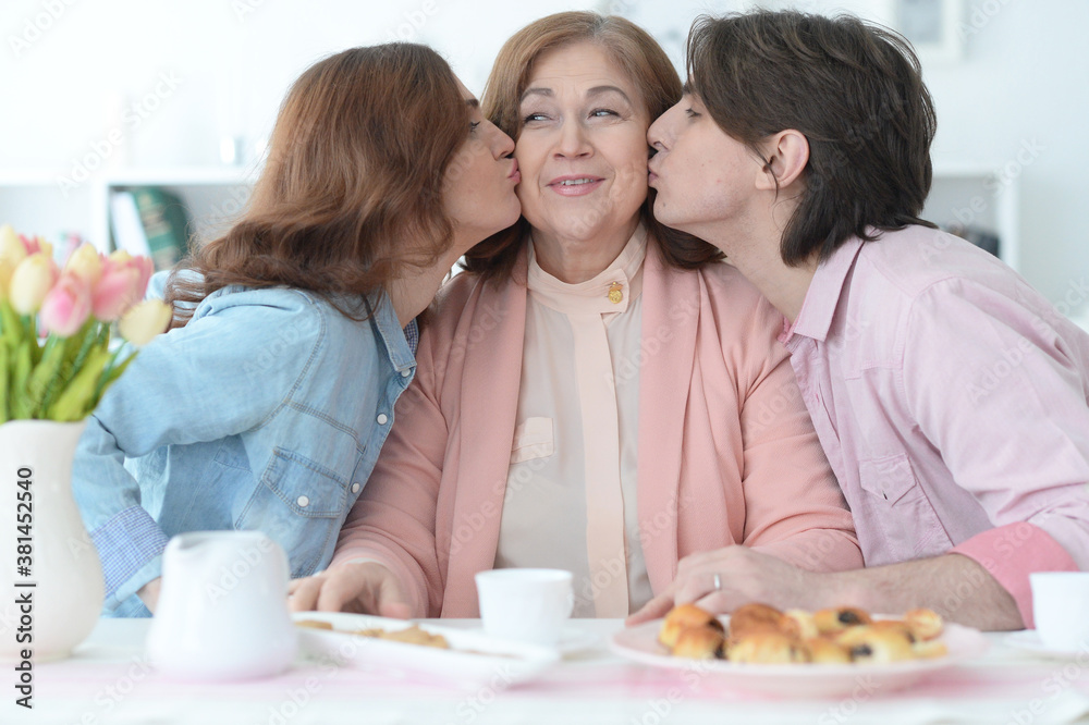 Family of three spending time together at dinner table with cookies and tea