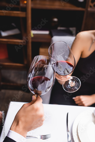 Cropped view of couple toasting with wine during dating in restaurant