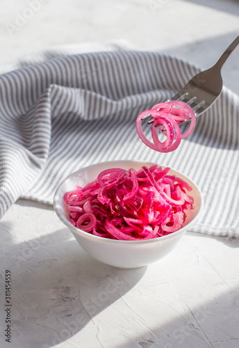 Juicy red onion marinated in lemon juice on a light background.