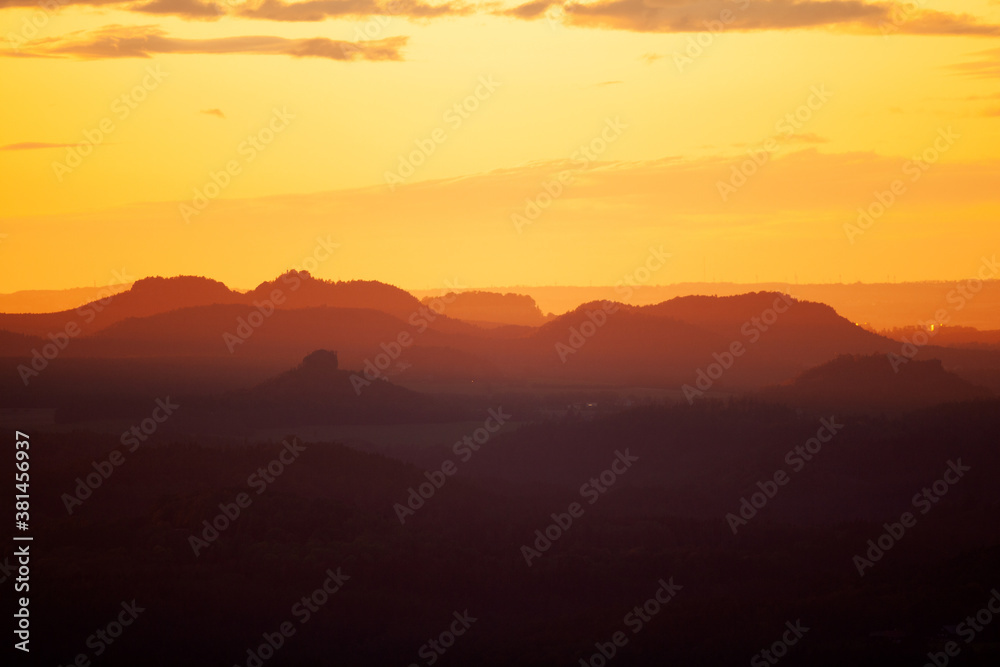 Hills during sunset. Orange light shining on the peak of mountains. Shapes of mountains during sunset.