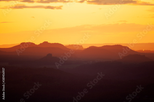 Hills during sunset. Orange light shining on the peak of mountains. Shapes of mountains during sunset. © prochym