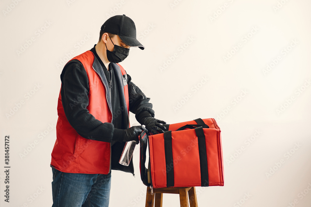 Delivery man courier online with box. Guy in uniform and protective face mask . Male squirt spray sanitizing. Corona virus concept. Delivery man courier online with box. Guy in uniform and protective face mask . Male squirt spray sanitizing. Corona virus concept.