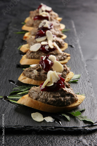 Snack. White toast bread with pate, jam and arugula on a black board. Sandwich crouton with pate. Background image, copy space