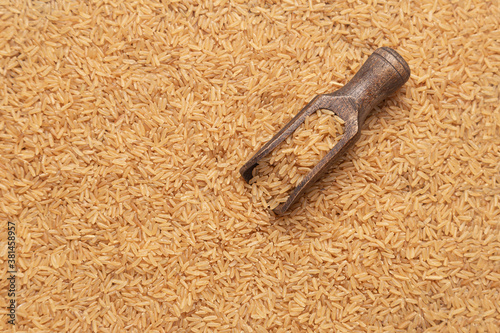 wooden spoon with brown rice on  brown rice background.
