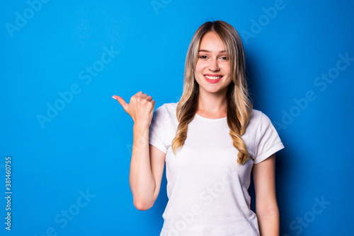 Young woman pointing finger to the side over isolated blue background