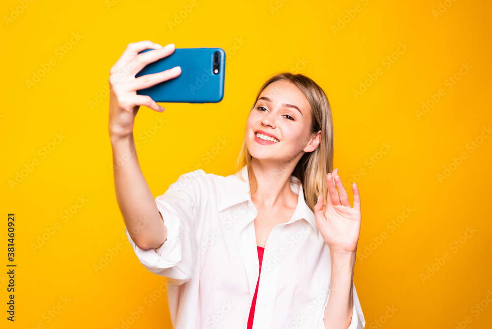 Young woman using cellphone have video call over yellow background Young woman using cellphone have video call over yellow background