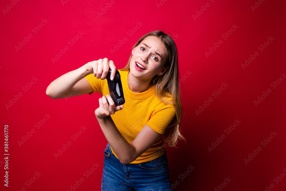 Young blonde gamer woman using gamepad playing video games over red background Young blonde gamer woman using gamepad playing video games over red background