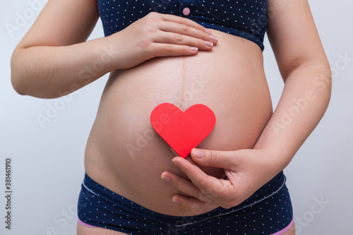Wallpaper Mural A pregnant woman holds a heart symbol against the background of her stomach Torontodigital.ca
