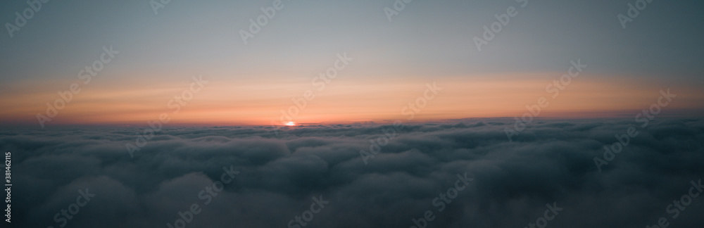 Aerial morning sunrise view over the clouds in the air with ocean fog and glowing clouds