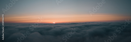 Aerial morning sunrise view over the clouds in the air with ocean fog and glowing clouds