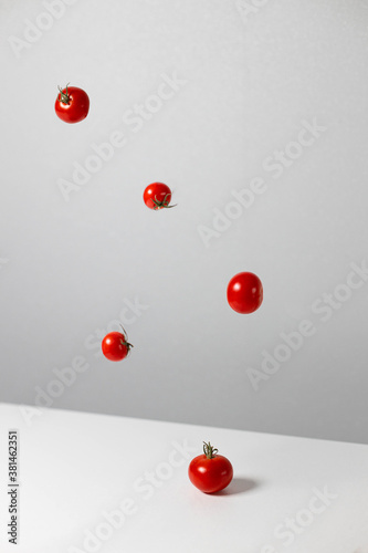 Creative composition of tomatoes in the air on gray table background. Vertical photo orientation