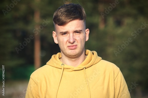 Portrait of young disappointed offended young man looking at camera with upset frustrated look outdoors