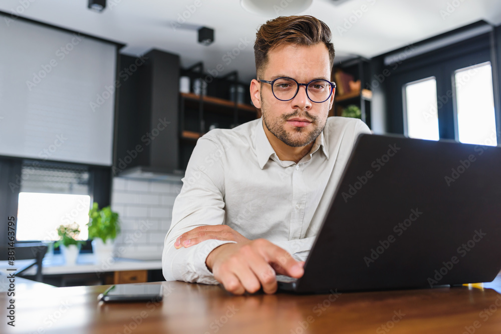 Young handsome man working from home, sitting in front of laptop computer having meeting over internet. Businessman freelance entrepreneur. Young handsome man working from home, sitting in front of laptop computer having meeting over internet. Businessman freelance entrepreneur.